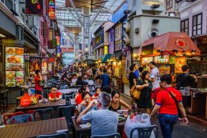 Vibrant Singapore nightlife with illuminated skyline, bustling streets, and people enjoying local food and shopping